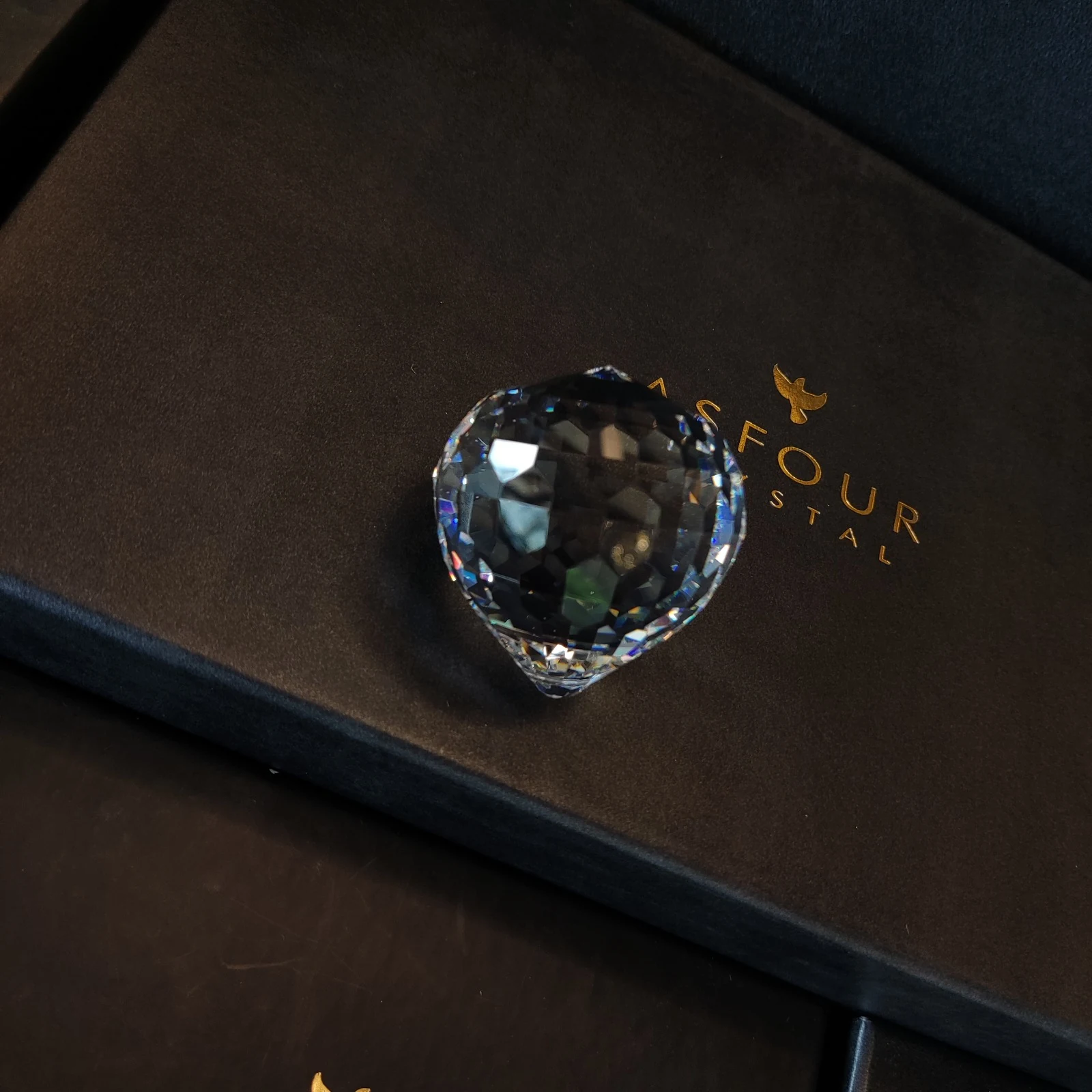 Cristal Asfour em formato de coração sobre a embalagem original